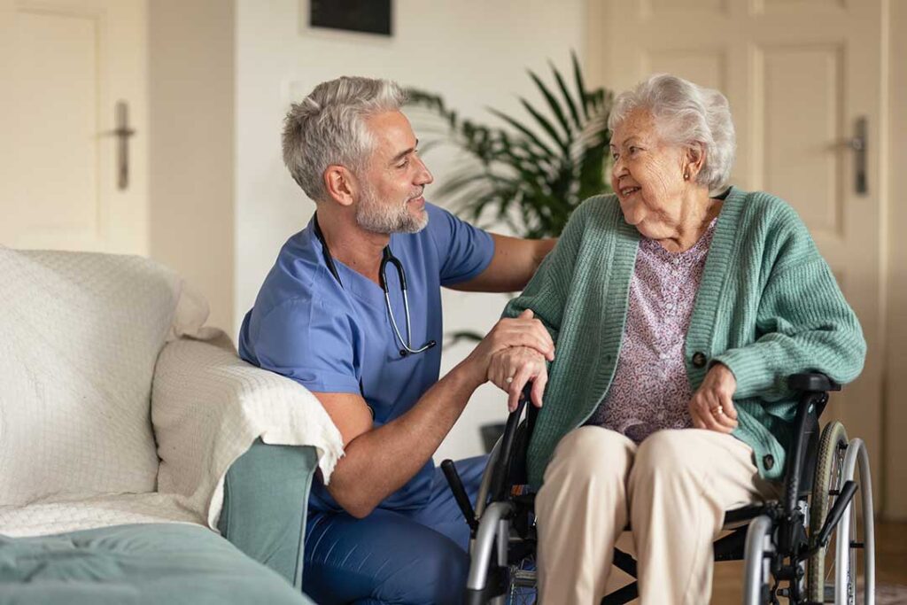 Adult child and older parent having a calm conversation at a kitchen table with notes and a cup of tea.